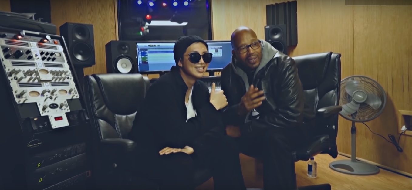 RM with Warren G in the music video for "P.D.D. (Please Don't Die)." Warren G produced the track for RM after getting to know him through the reality series "American Hustle Life."
