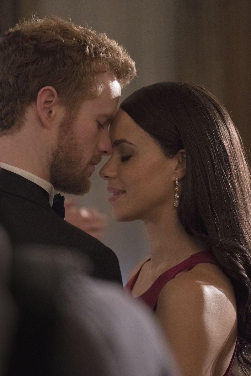 Murray Fraser and Parisa Fitz-Henley as Prince Harry and Meghan Markle, both poshly dressed with eyes closed in a loving embrace.