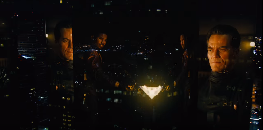 A city at night featuring images of Michael Shannon and Michael B. Jordan transposed onto the building faces. Jordan is shown burning something, probably a bunch of books. 