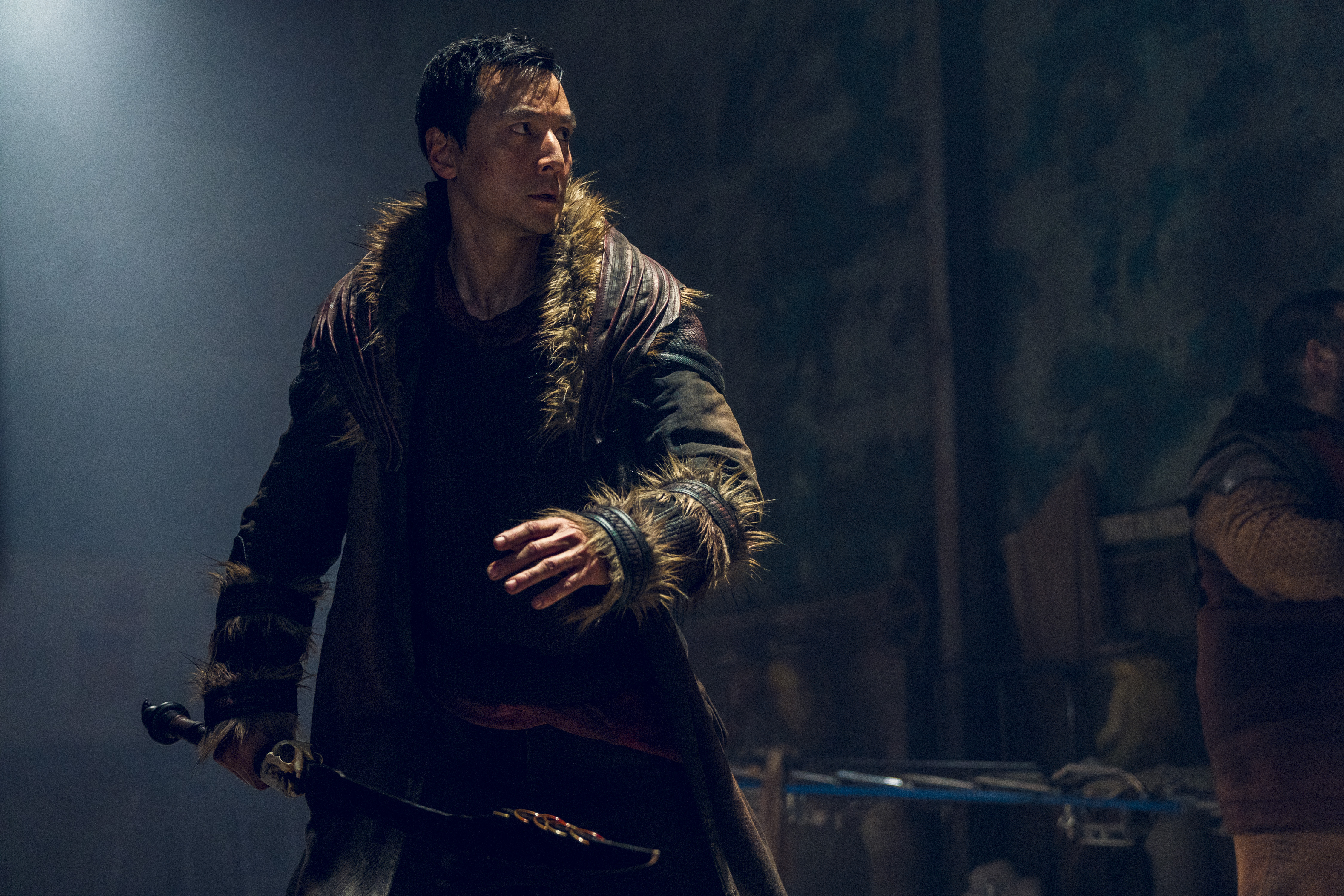 Daniel Wu as Sunny. He's wearing a fur-lined coat and holds his sword. 