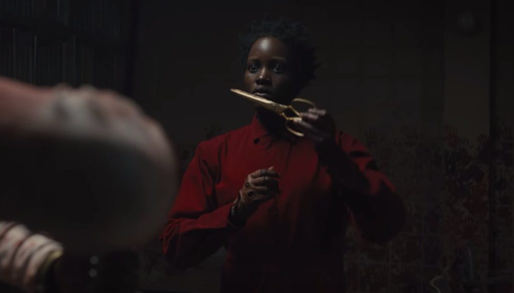 Lupita Nyong'o's evil self, wearing a red jumpsuit and golden scissors
