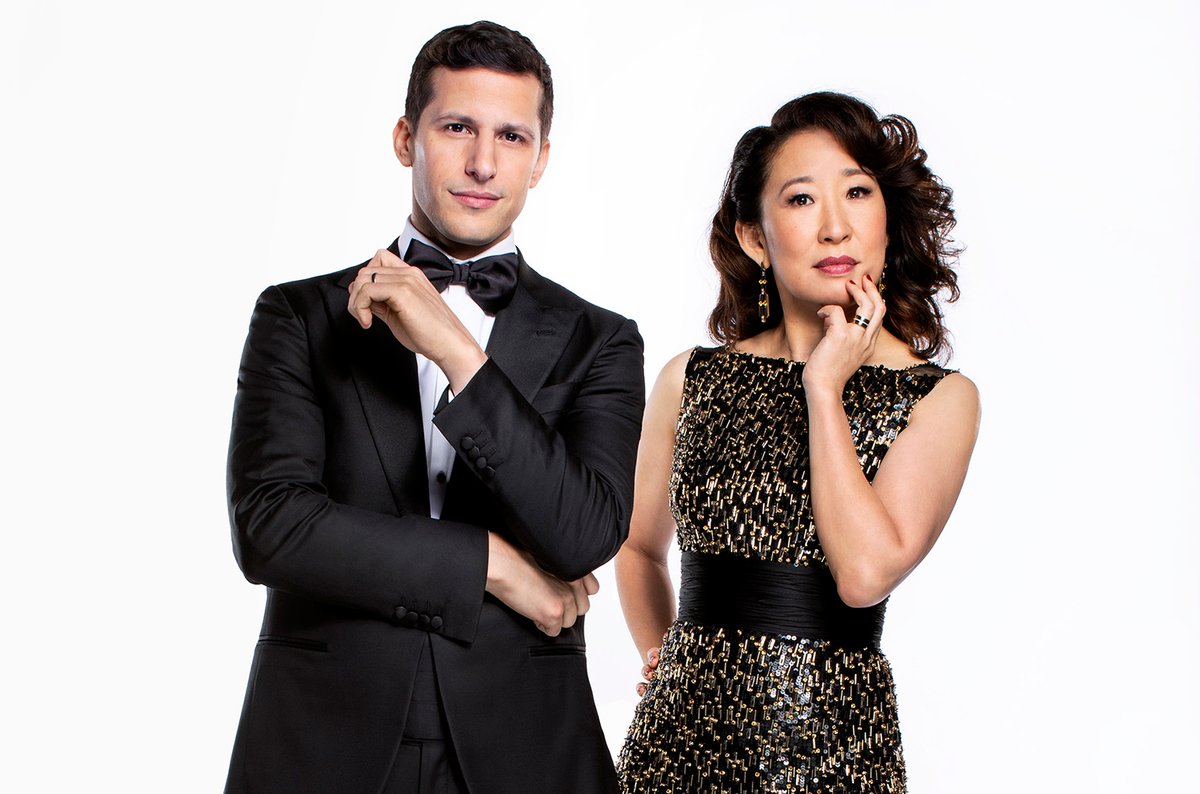 Andy Samberg and Sandra Oh, wearing their black tie best (Samberg in a traditional tux and Oh in a black and gold-tipped dress), pose for a promo shoot for the Golden Globes.