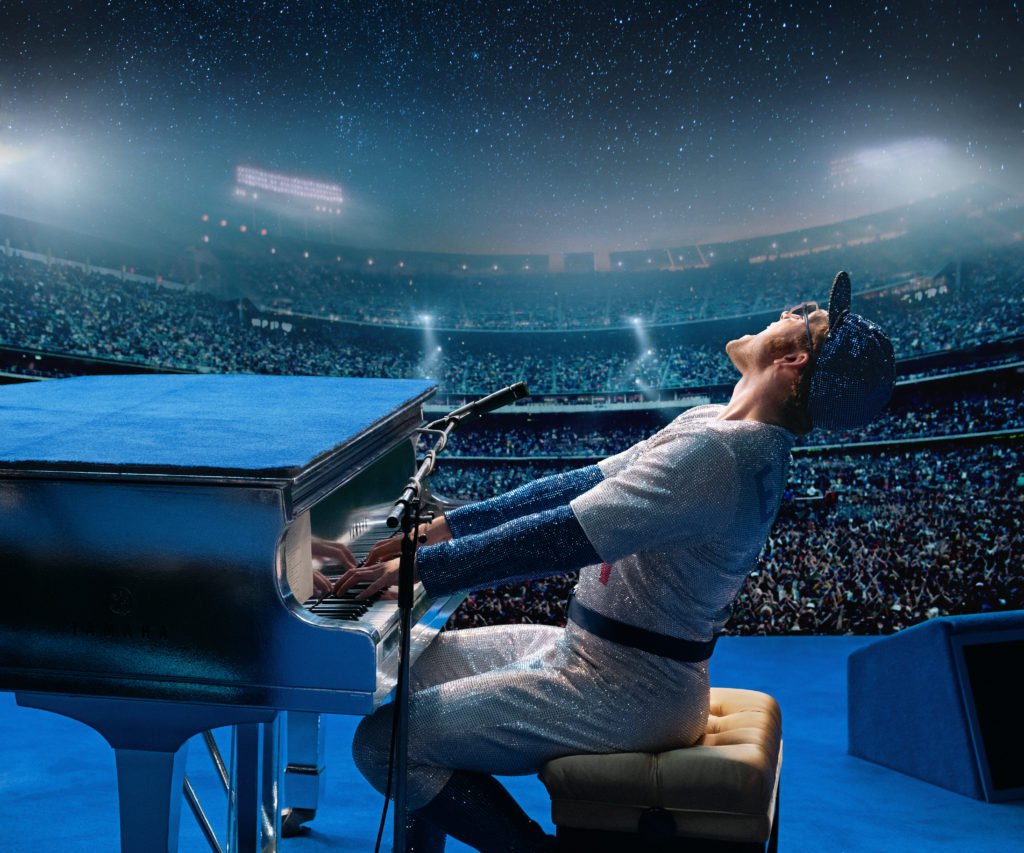 Taron Egerton as Elton John in Rocketman from Paramount Pictures. Elton John is wearing his sequined baseball uniform as he performs to a sold-out crowd. 