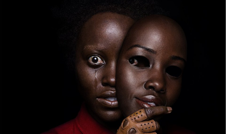 The black poster for US, featuring a crying Lupita Nyong'o as Red holding a mask of Lupita's face. She is wearing a leather glove and a red jumpsuit. 