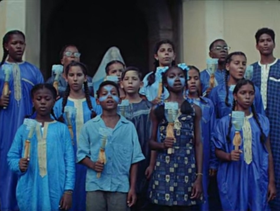  A chorus of young Cuban children of different racial backgrounds wear blue and sing with homemade candle holders. 