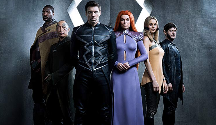 The cast of the Inhumans stand in front of a gray background
