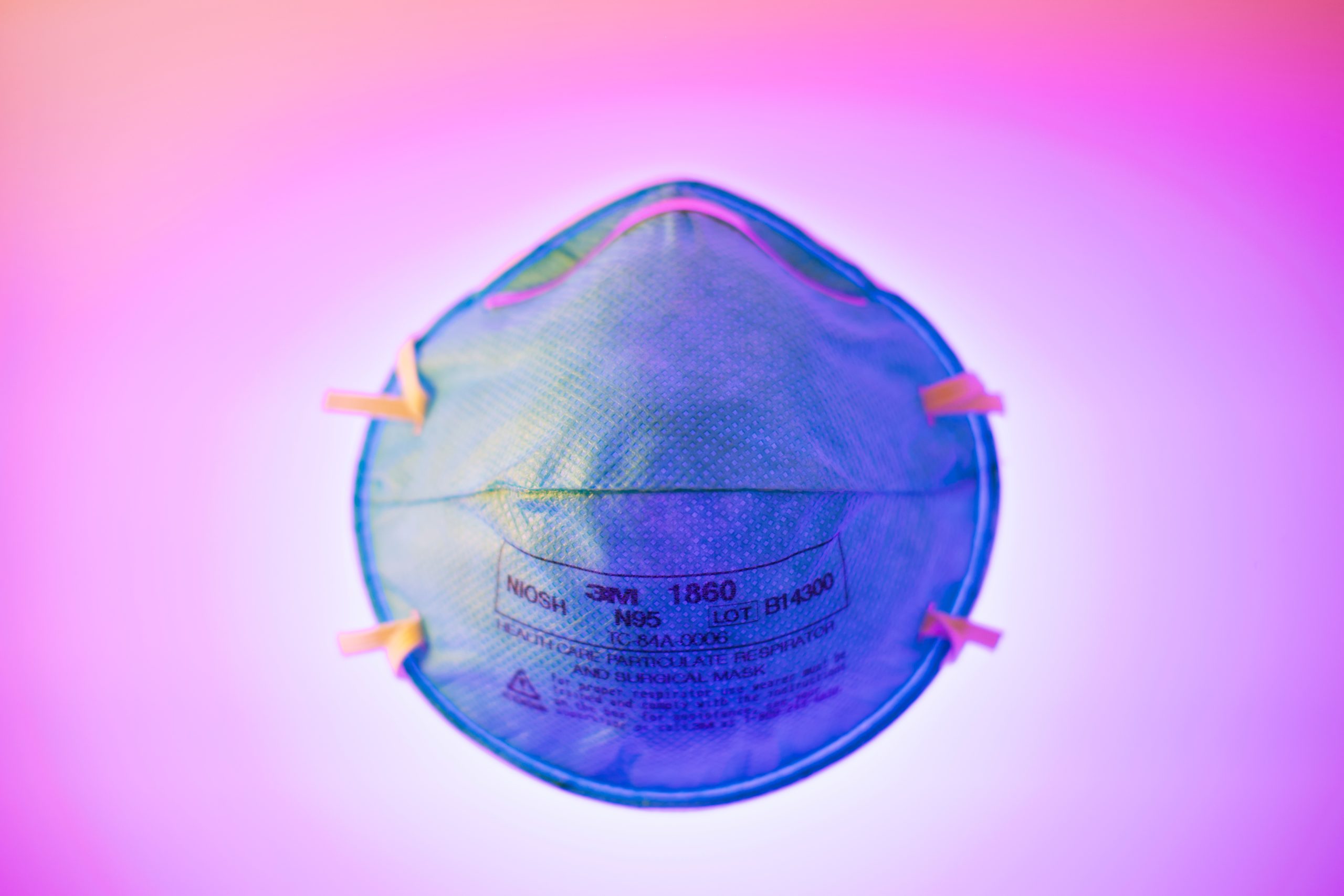 Here's how COVID-19 is affecting the LGBTQ community. Face mask light with blue light amid pink-lit background. Photo by Brian McGowan on Unsplash