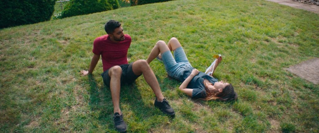 Ritesh Rajan and Sujata Day as Sunny and Monica sitting on the grass in Definition, Please. (Photo credit: June Street Productions)