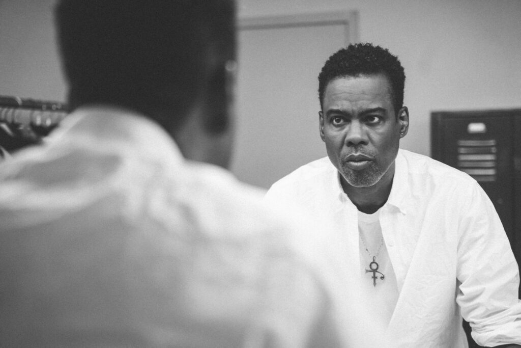 Chris Rock in a white shirt with a Prince symbol necklace before his special, Selective Outrage (Photo credit: Netflix)