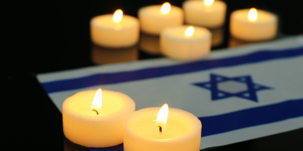 Burning candles with flag of Israel on dark background. (Photo credit: Pixelshot/Canva)